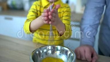 非常可爱的小男孩在厨房里搅拌鸡蛋。 做炒鸡蛋。 可爱的爸爸，可爱的小男孩